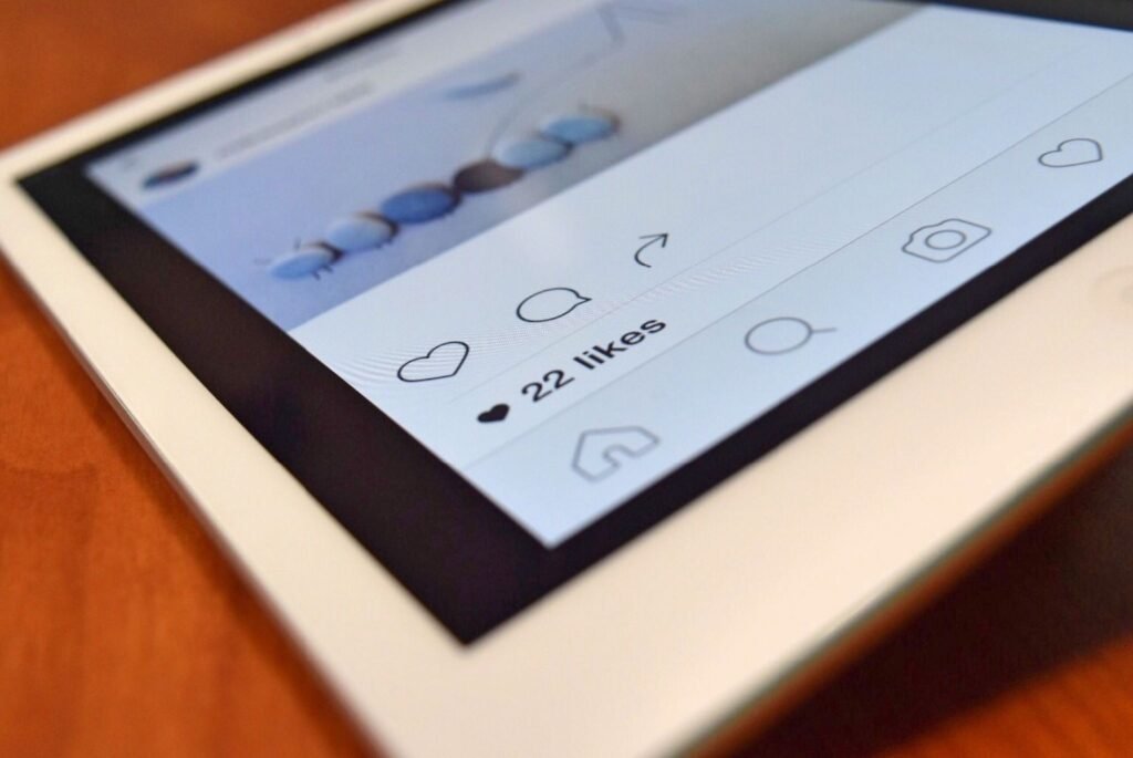A close-up view of a tablet screen showing a social media feed with icons for liking, commenting, sharing, searching, and a post that has received 22 likes.